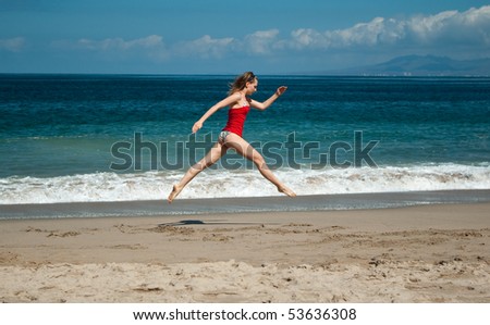 Young beautiful slim girl doing a small jetÃ© (ballet jump) at the beach near Pacific ocean