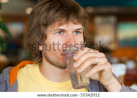 Handsome young man with grey eyes having a glass of water