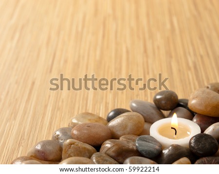 Zen candle in pebbles with wood background