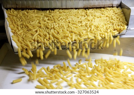 PARMA, ITALY - 3 OCTOBER 2012: Tortiglioni pasta falling from a spout as they travel along the production line inside a pasta factory.