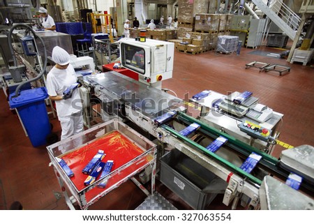 PARMA, ITALY - 3 OCTOBER 2012: An employee checking boxes of packaged pasta for quality control as they travel along the production line inside a pasta factory.