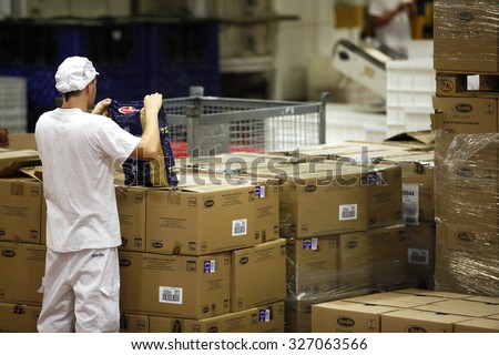 PARMA, ITALY - 3 OCTOBER 2012: An employee checking boxes of packaged pasta for quality control along the production line a pasta factory.