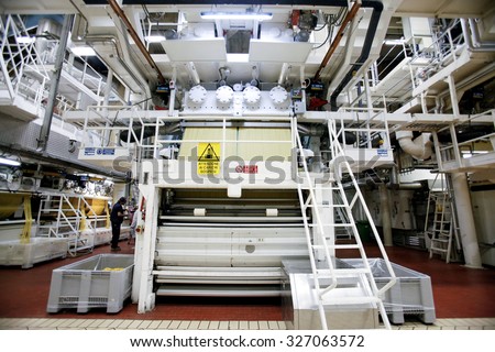 PARMA, ITALY - 3 OCTOBER 2012: Strands of spaghetti are processed ahead of packaging on the production line inside a pasta factory.