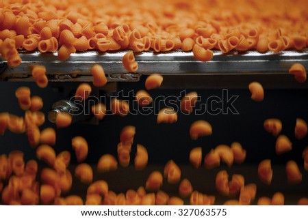 PARMA, ITALY - 3 OCTOBER 2012: Orange pasta made with carrot moving along the production line inside a pasta factory.