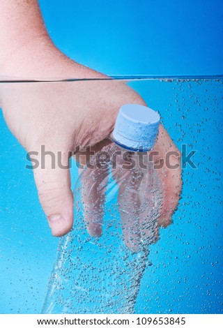 water bottle in his hand submerged in blue water