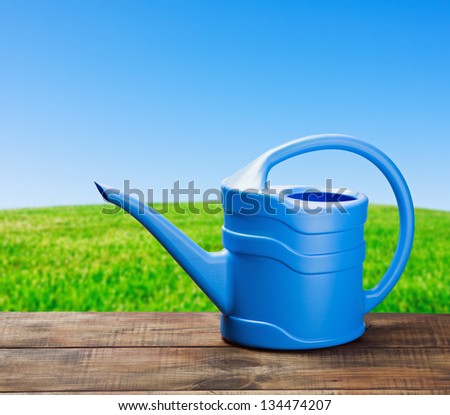 blue watering can to water on a wooden table