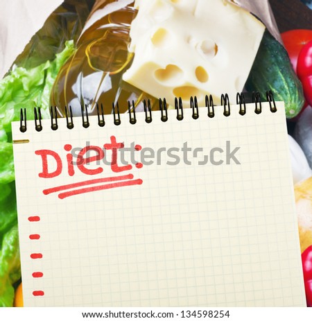 notebook with diet plan against food supermarket