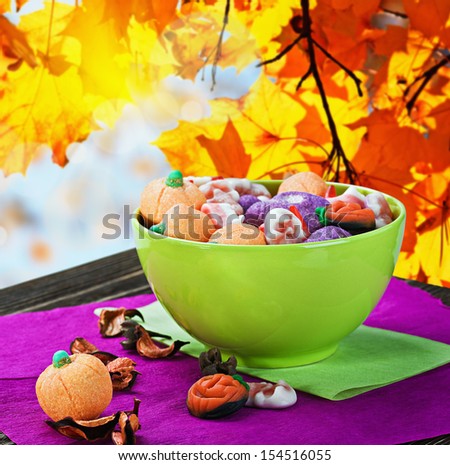 sweets and candies for the holiday halloween on a batskground autumn leaves
