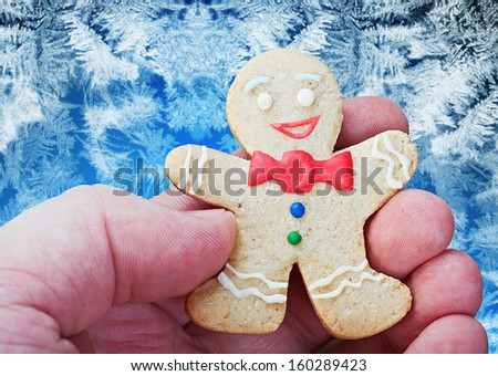 smiling gingerbread man in the hand against frost