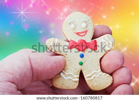 smiling gingerbread man in a hand on a background color