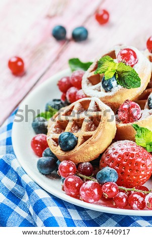 Waffles with fresh berries on the table. Focus on berries in the foreground. Shallow depth of field