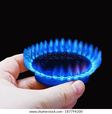 Hands holding a flame gas fone. Fokus black on the front edge of the gas hobs