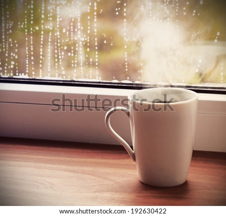 cup of hot coffee on the window sill wet from the rain. Toned image