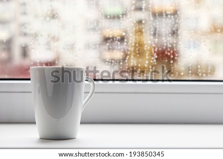 cup of hot coffee on the window sill wet from the rain