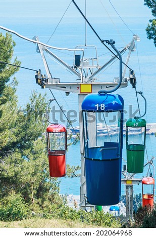 Multicolored cabins of cable railway. Focus on the red booth and metal support