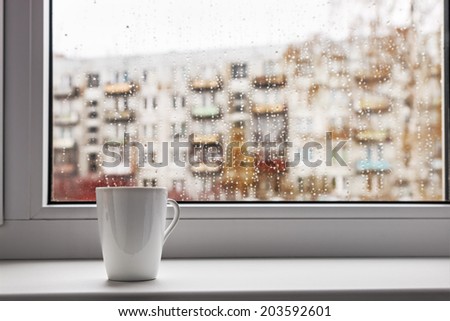 cup of hot coffee on the window sill wet from the rain