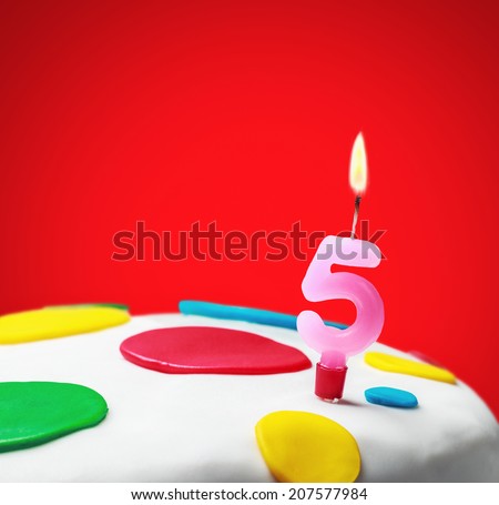 Burning candle with the number five on a birthday cake. birthday greetings