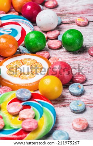 multicolored sweets and chewing gum on a wooden table. focus on green gum balls