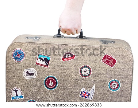hand holding a retro suitcase with stickers isolated on white background.