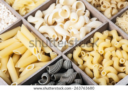 assortment of pasta in a wooden box background. focus on foreground, black paste