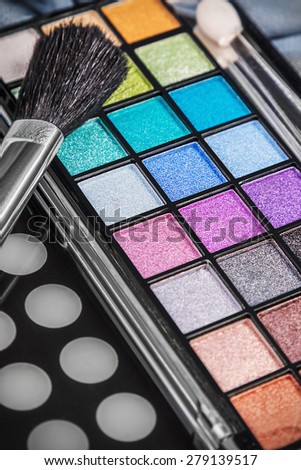 Make-up colorful eyeshadow palettes with makeup brushes. Focus in the middle of the frame on the blue shadows. Shallow depth of field