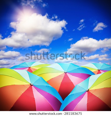 Rainbow umbrellas against the background of the sunny sky. focus on the foreground umbrellas