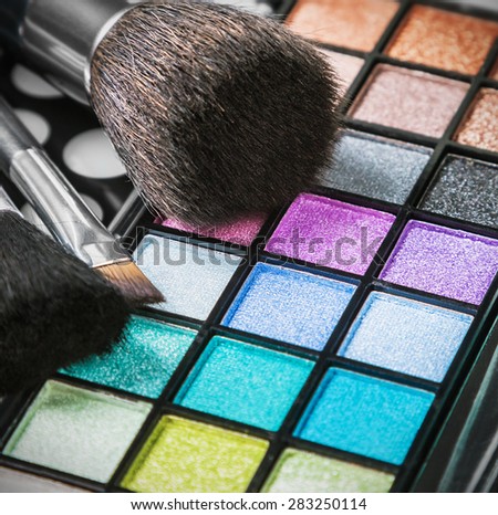 Make-up eyeshadow palettes with makeup brushes. Focus in the middle of the frame on the blue shadows. Shallow depth of field