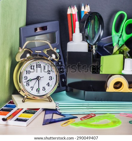 alarm clocks and school supplies on the school desk. Focus on the alarm clock