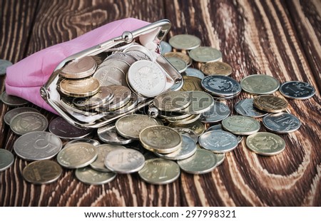 Purse with money on old rustic wooden table. Focus on the coins in the purse