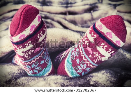 Female legs in Christmas socks under a blanket of fur. toning image