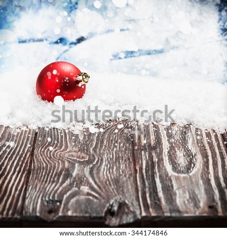 Christmas ball on a wooden table in the snow. focus on Christmas ball