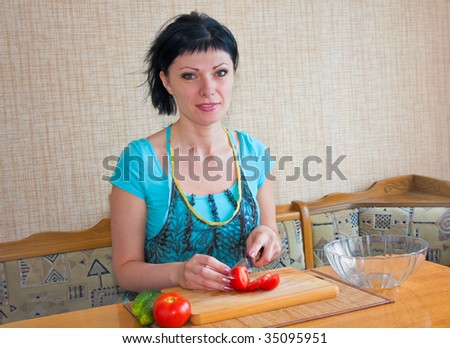 young woman in the kitchen cut the tomatoes and cucumbers