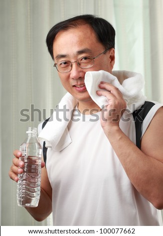 Man in a gym with bottle of water and a towel