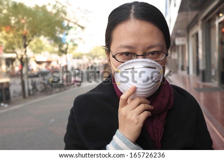 Woman with face mask on a polluted city street
