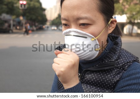 Asian woman wearing a protective face mask on a city street with air pollution