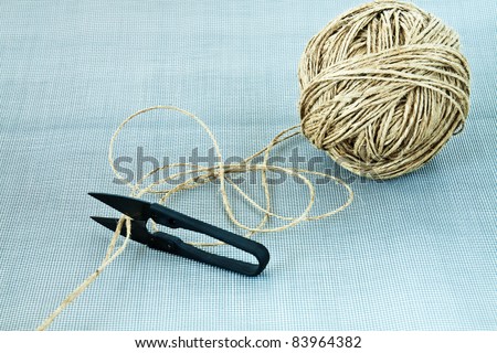 Rolled ball of twine with small scissors on a mesh background