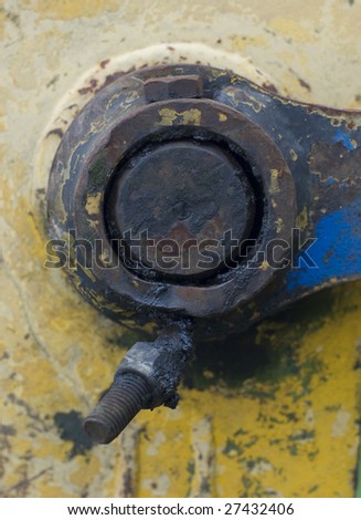 Greasy industrial swing arm joint and bolts set against a damaged yellow metal surface