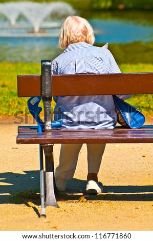 Old woman sitting on bench in park