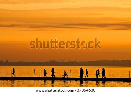 Group of people walking on boardwalk at sunset