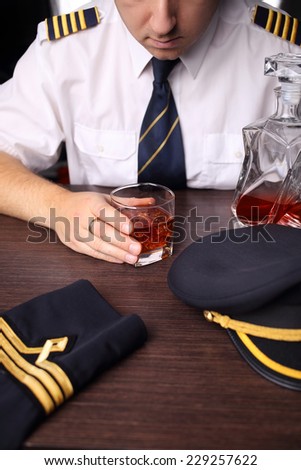 The pilot in uniform drinking alcohol