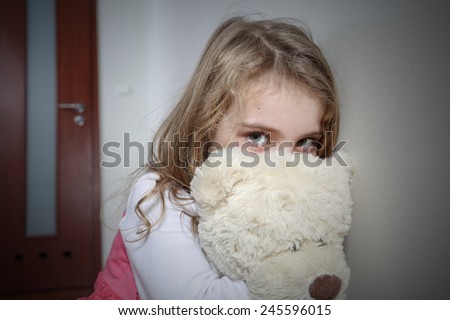 Young sad girl hugging a teddy bear