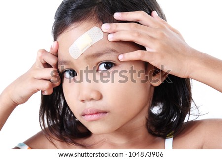 Young girl showing a wound plaster in her head.