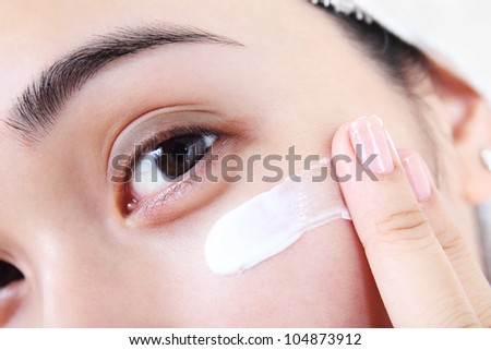 Asian woman applying facial lotion or moisturizer on her face.Close up.