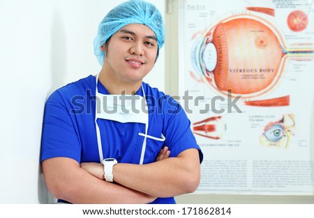 Ophthalmologist standing beside a poster of eye anatomy.