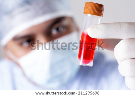 Scientist studying a tube with a chemical for vaccine research. Close up.