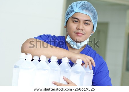 Portrait of a handsome young male asian nurse with IV fluids.