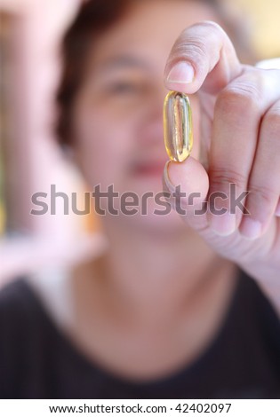 close up of yellow pill in womans hand