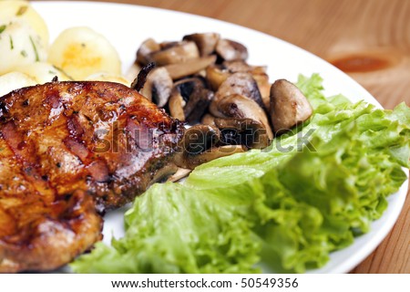 Tasty grilled food, chicken meat, roasted potatoes and mushrooms and sallet