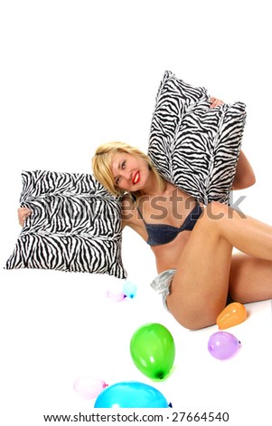 Half body view of young attractive woman in bikini, sitting on floor whit zebra pillows. Isolated on white background.