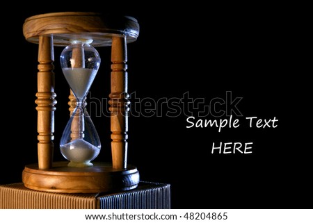Vintage wood hourglass with cold light, isolated on black. Free space for custom text on the right